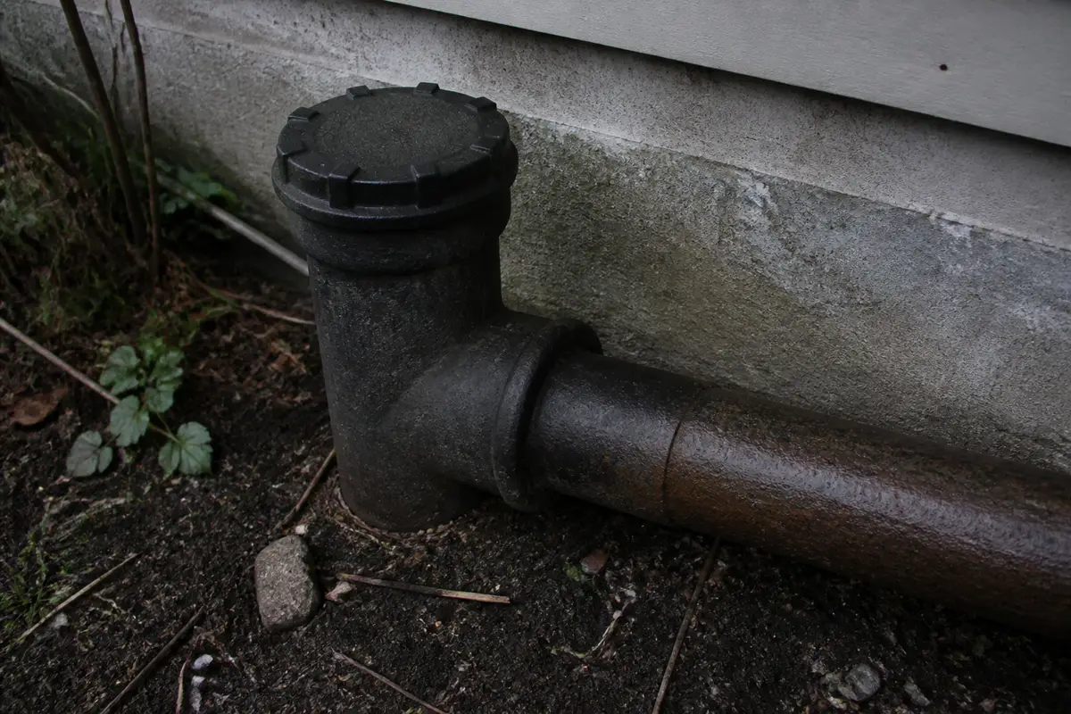 Exterior sewer cleanout pipe at a house foundation
